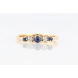 A sapphire and diamond five stone ring, set with three graduated round cut sapphires separated by