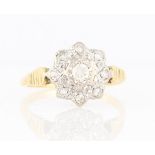 A diamond set flower design ring, set with a central round brilliant cut diamond, measuring