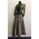 A 19th century two piece ladies outfit in green and grey with button up top.