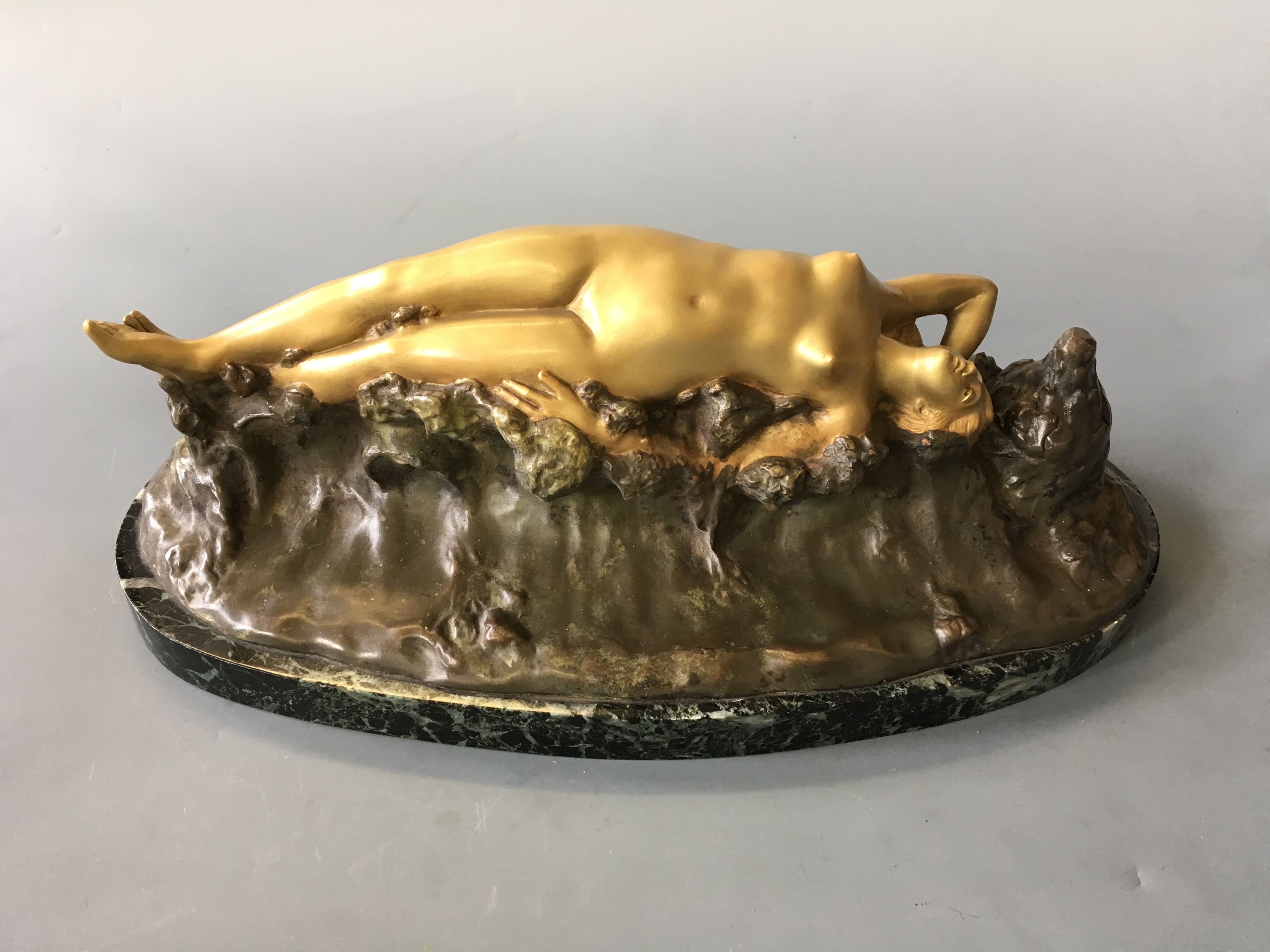 DROUARD. A signed, gilded bronze nymph lying on waves, on black and green marble base, length of