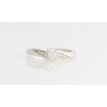 A 9ct white gold diamond ring, set with a principal central round brilliant cut diamond, measuring