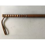 A wooden night stick with leather strap.