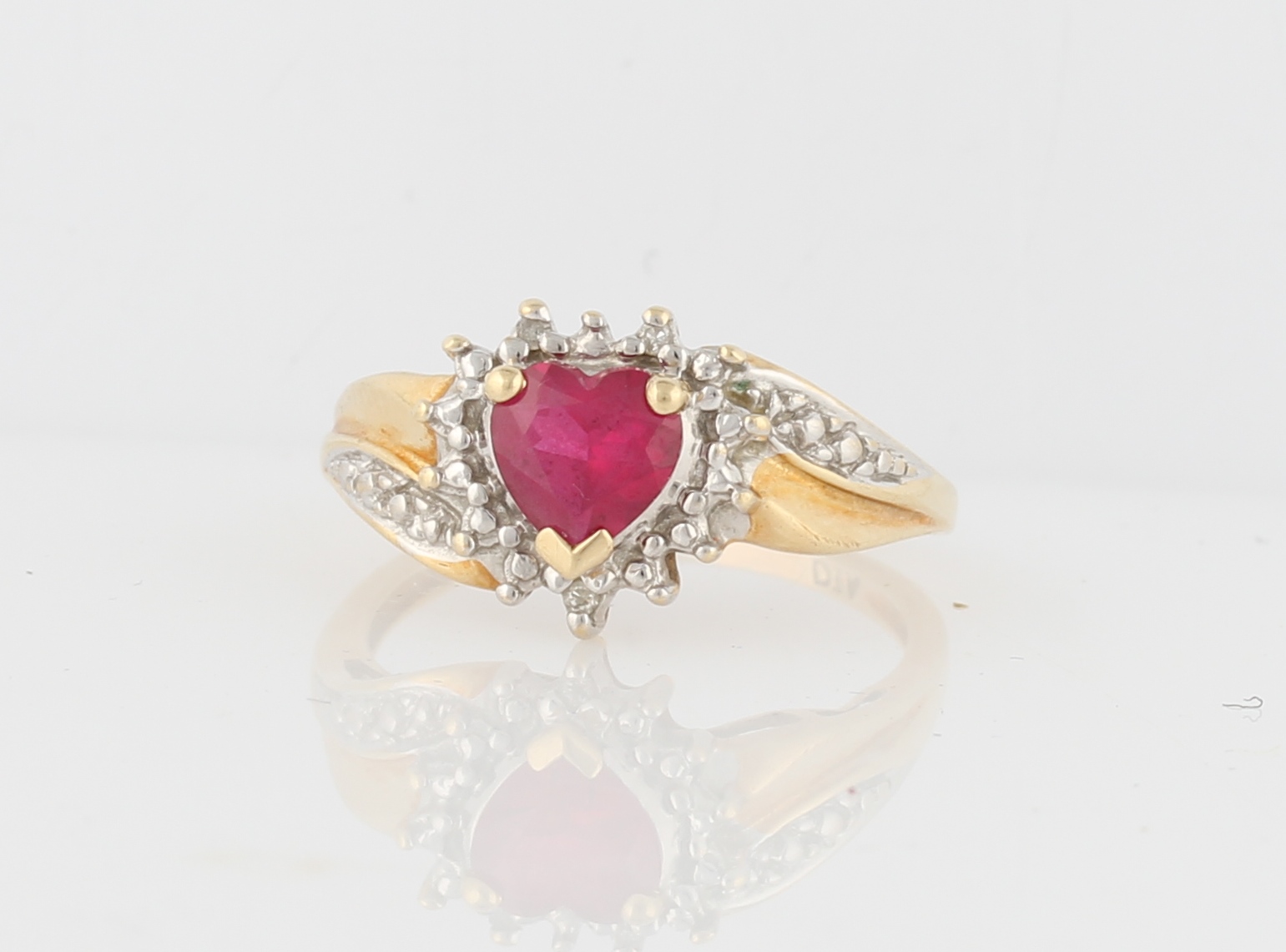 A hallmarked 9ct yellow gold ruby and diamond ring, set centrally with a heart cut ruby (possibly