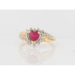 A hallmarked 9ct yellow gold ruby and diamond ring, set centrally with a heart cut ruby (possibly