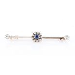 A sapphire and diamond bar brooch, set with a central round cut sapphire surrounded by a border of