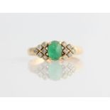 An emerald and diamond ring, set with a central oval emerald cabochon, measuring approx. 6x4mm,