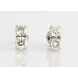 A pair of two stone diamond earrings, each stud set with two round brilliant cut diamonds, each