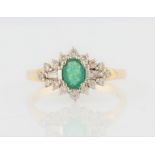 A hallmarked 9ct yellow gold emerald and diamond cluster ring, set with a central oval cut