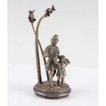 A white metal ornament of a man with child in front of trees, holding arrows and crossbow, unmarked,