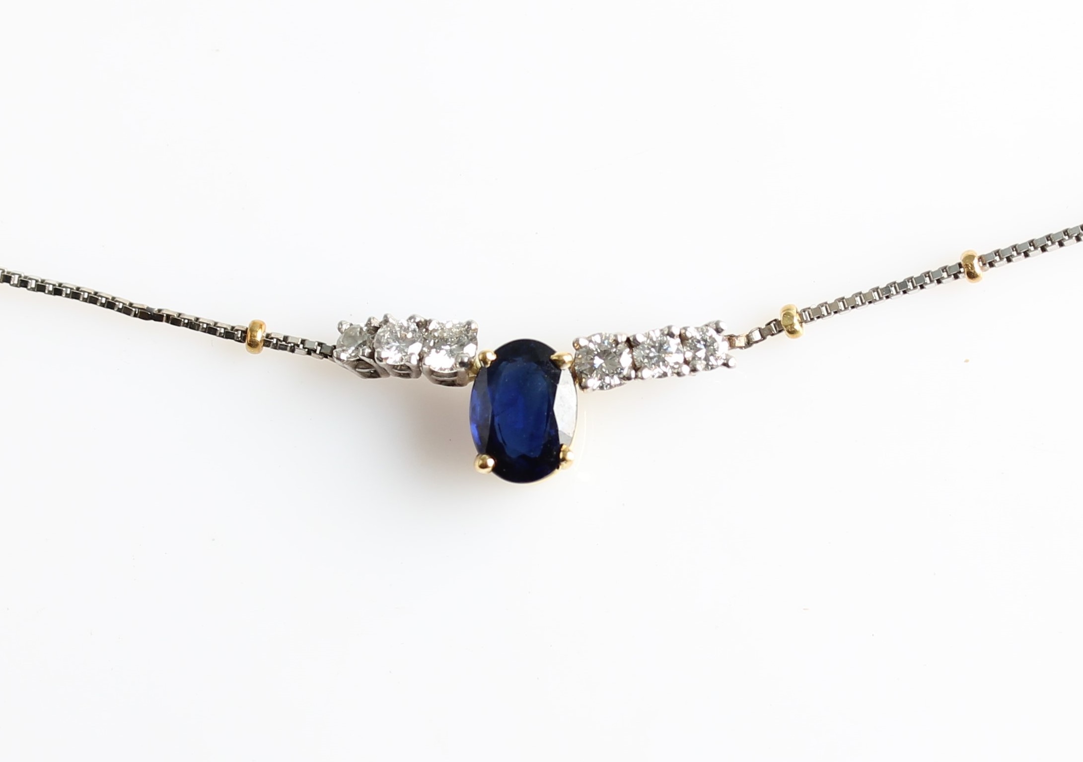 A hallmarked 18ct yellow and white gold sapphire and diamond necklet, set with a central oval cut