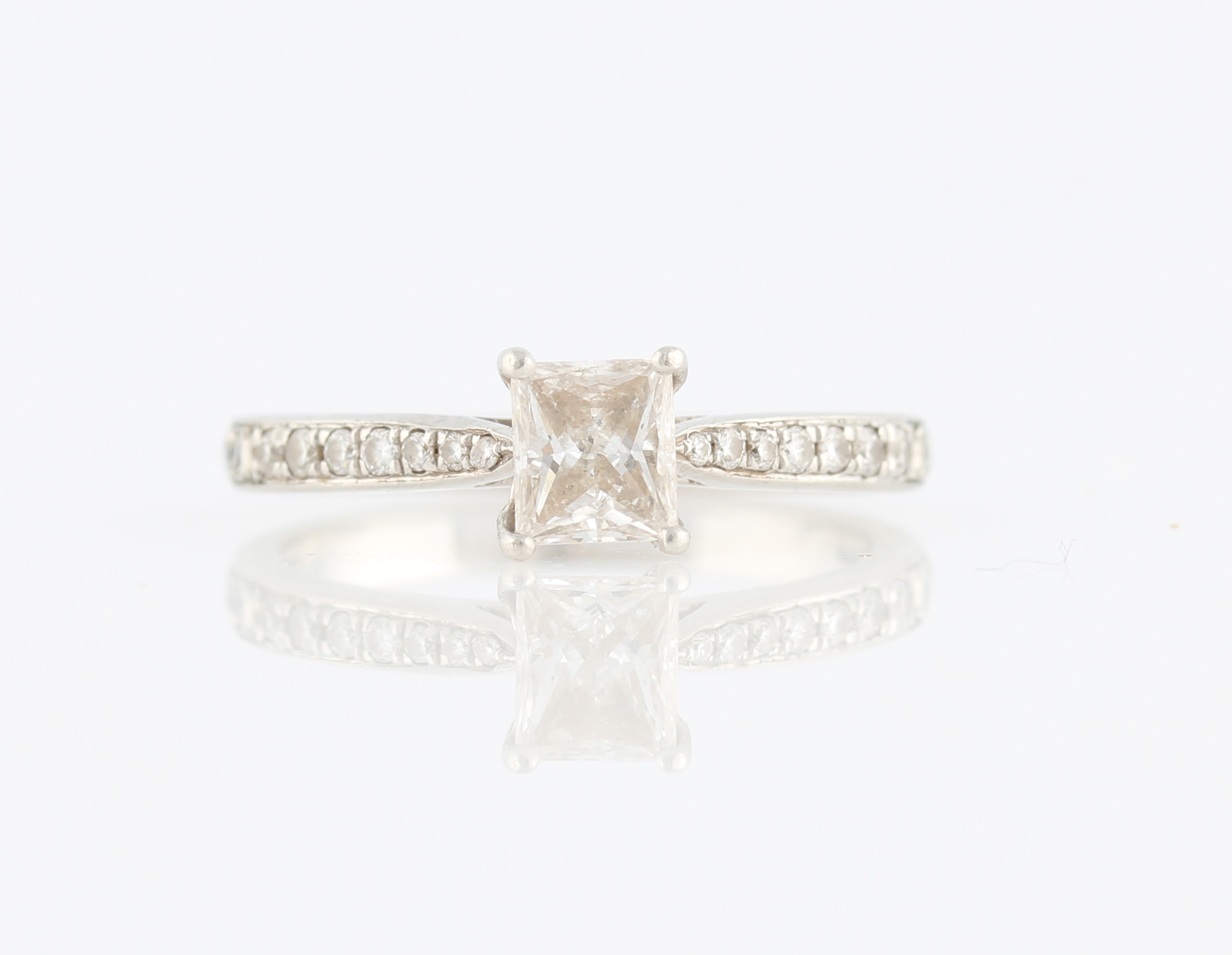 A platinum diamond ring, set with central rectangular princess cut diamond, measuring approx. 0.