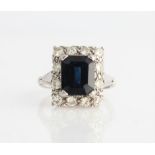 A sapphire and diamond cluster ring, set with an emerald-cut sapphire, measuring approx. 9x7mm,