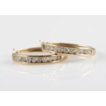 A pair of hallmarked 9ct yellow gold diamond hoop earrings, each channel set with ten round