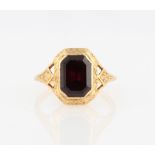 A garnet ring, set with an emerald cut garnet, measuring approx. 2 ½ct, with engraved leaf design to