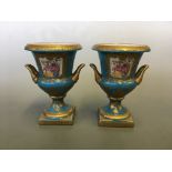 A pair of Sevres style two handled urns on blue and gilded background, height 20cm.