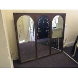 A mahogany framed triple bevelled edged mirror, each frame with arched top, with bevelled floral