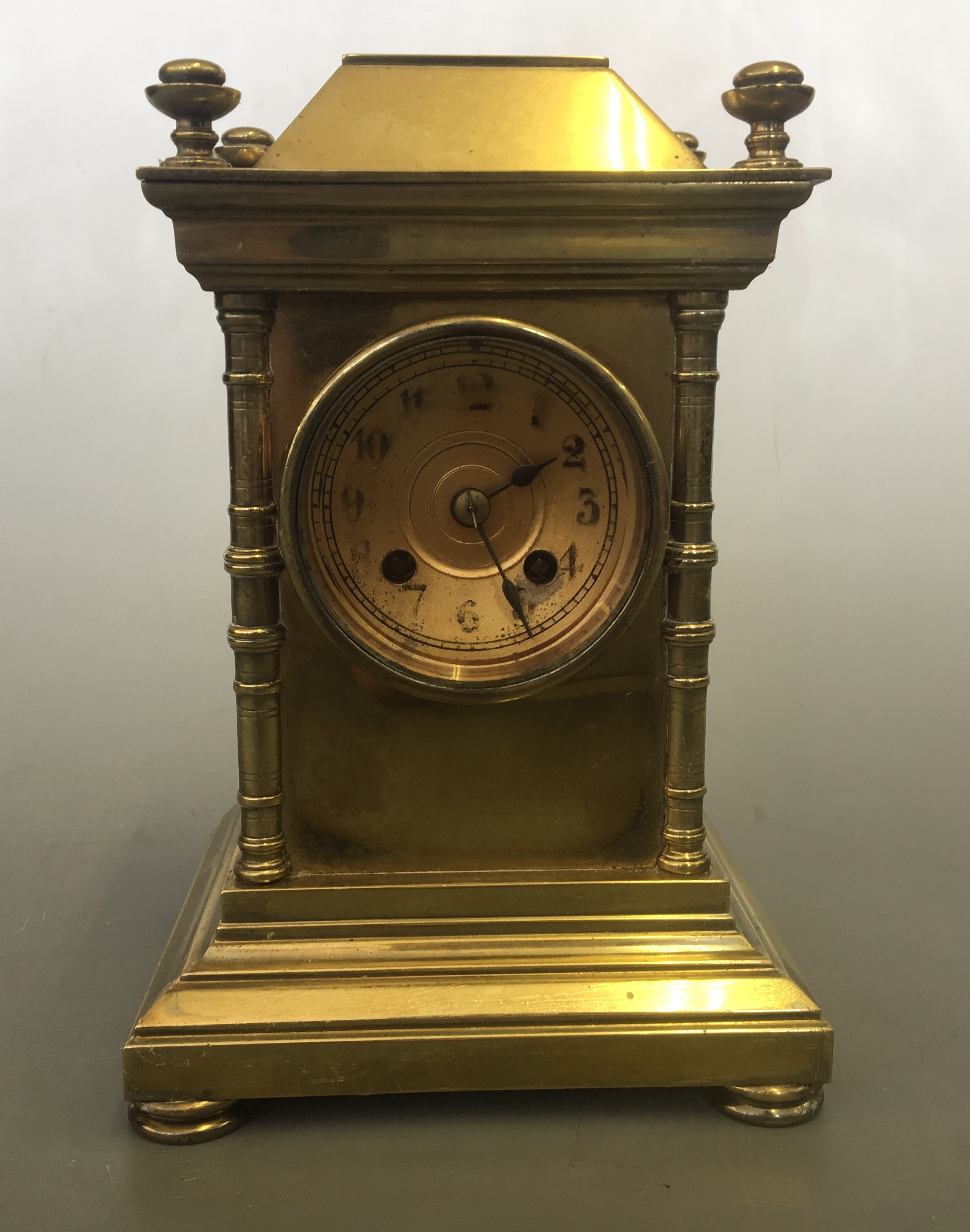 A solid brass cased mantel clock with column design, four finials to top, 21.5cm x 14.5cm x 12.5cm.