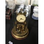 A brass anniversary clock with glass dome.