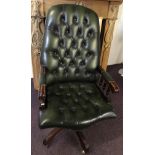 A green leather upholstered button backed swivel chair.