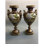 A pair of Empire style urns with deep blue backgrounds, gilded border and fishing scenes, on brass