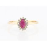 A hallmarked 9ct yellow gold ruby and diamond cluster ring, set with an oval cut ruby surrounded