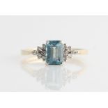 A hallmarked 9ct yellow gold blue topaz and diamond ring, set with a central emerald cut blue topaz,