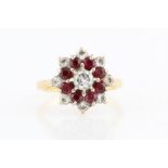 A hallmarked 18ct yellow gold ruby and diamond tiered cluster ring, set with a central round