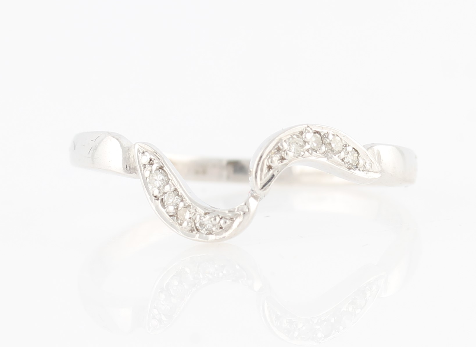 A hallmarked 9ct white gold diamond band ring, the waved design set with eight-cut diamond