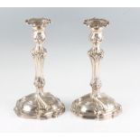 A pair of candlesticks, having removable fluted sconces, knopped stems and raised on a scroll