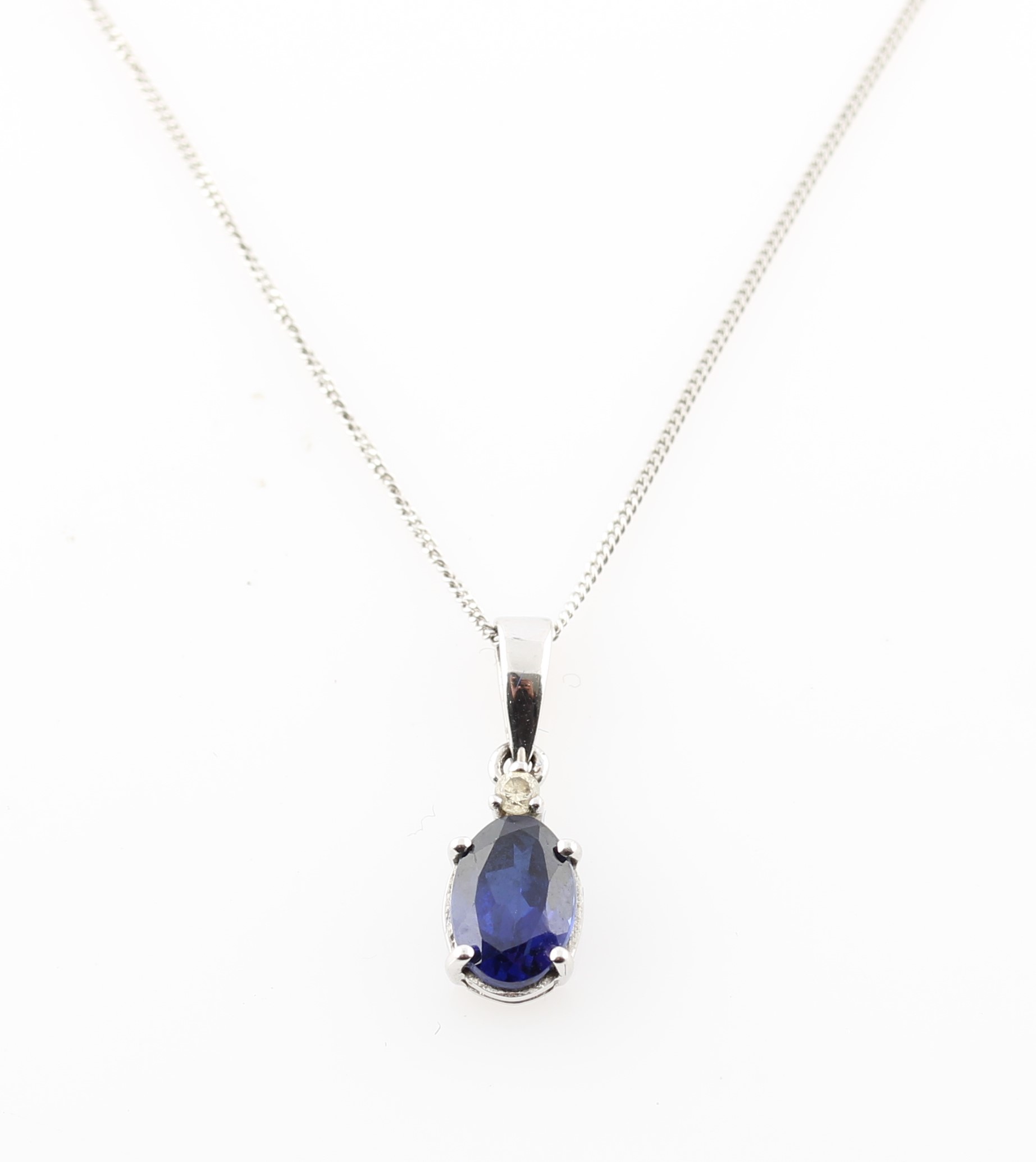 A synthetic sapphire and diamond pendant, set with a central oval cut synthetic sapphire,