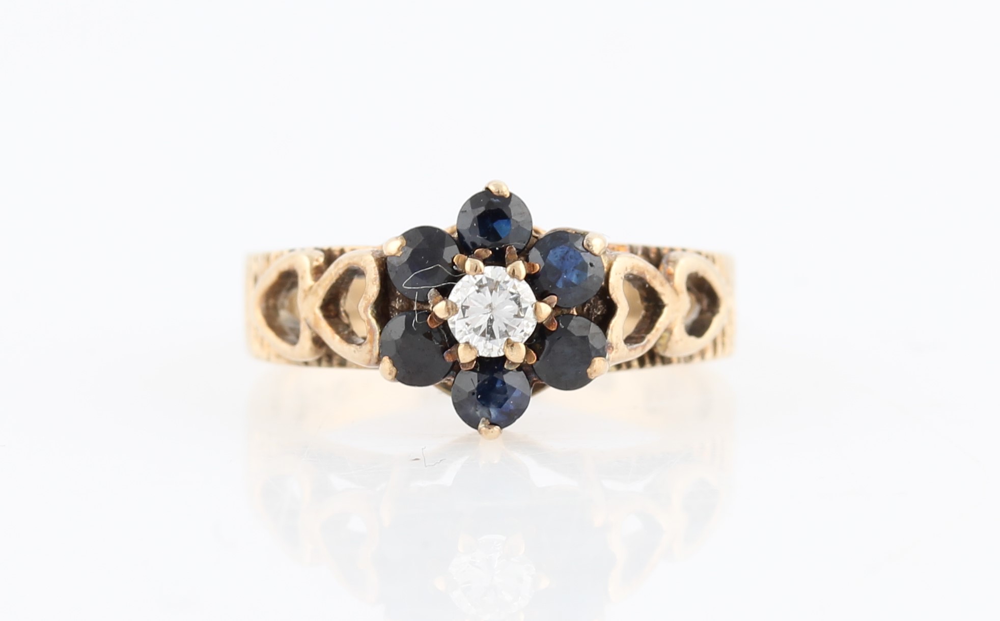 A diamond and sapphire flower cluster ring, set with a central round brilliant cut diamond