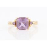 An amethyst dress ring, set with a principal cushion cut amethyst, flanked to either side with a