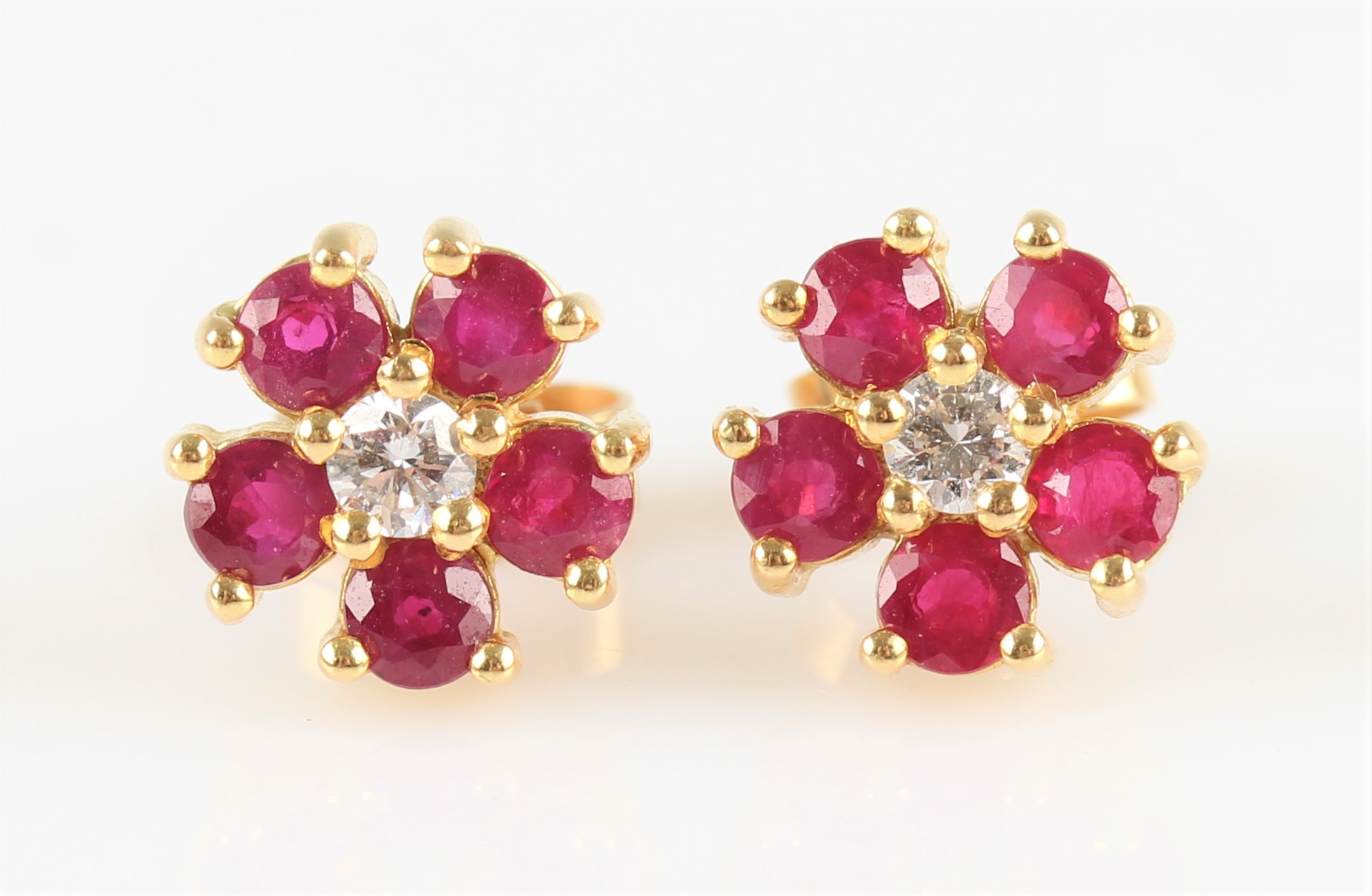 A pair of ruby and diamond flower design cluster earrings, each set with a central round brilliant