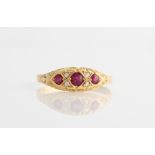 An 18ct yellow gold ruby and diamond ring, set with three principle round cut rubies, separated by