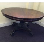 A Victorian mahogany told topped round table on carved leave base