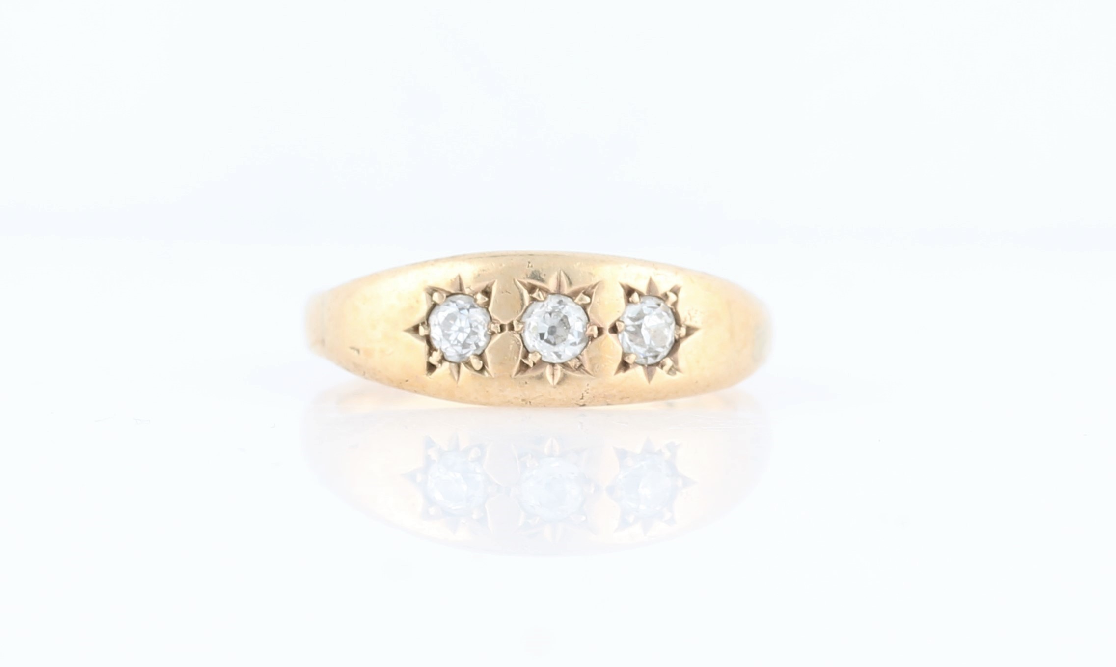 A three stone diamond ring, star set with three old cut diamonds, total diamond weight approx. 0.