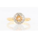 A hallmarked 18ct yellow gold topaz and diamond cluster ring, set with a central round cut topaz,