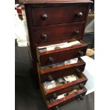 A mahogany six drawer chest containing a large selection of coins in plastic wallets.