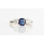 A sapphire and diamond three stone ring, set with a central square cut sapphire, flanked to either
