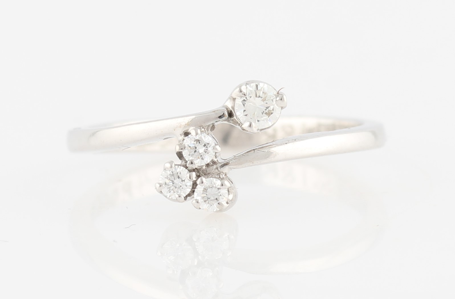 A hallmarked 18ct white gold diamond ring, the cross over design set at one end with a single