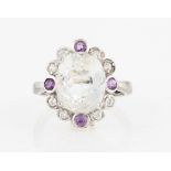 A topaz and amethyst dress ring, set with a central oval cut colourless topaz surrounded by a border
