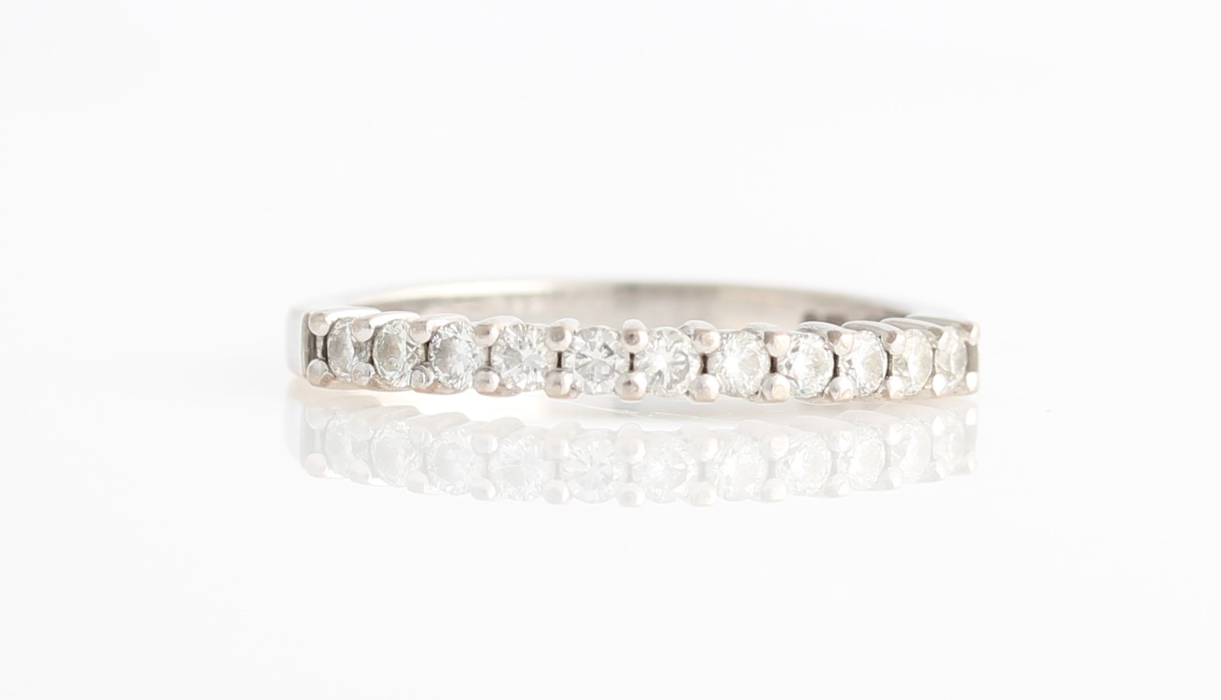 A hallmarked 18ct white gold diamond half eternity ring, set with eleven round brilliant cut