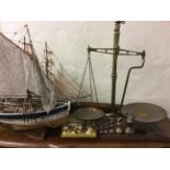A set of brass and mahogany scales with graduated bell weights, together with two model ships and