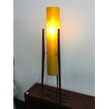 An orange cylinder mid century floor standing light fitting standing on three legs.