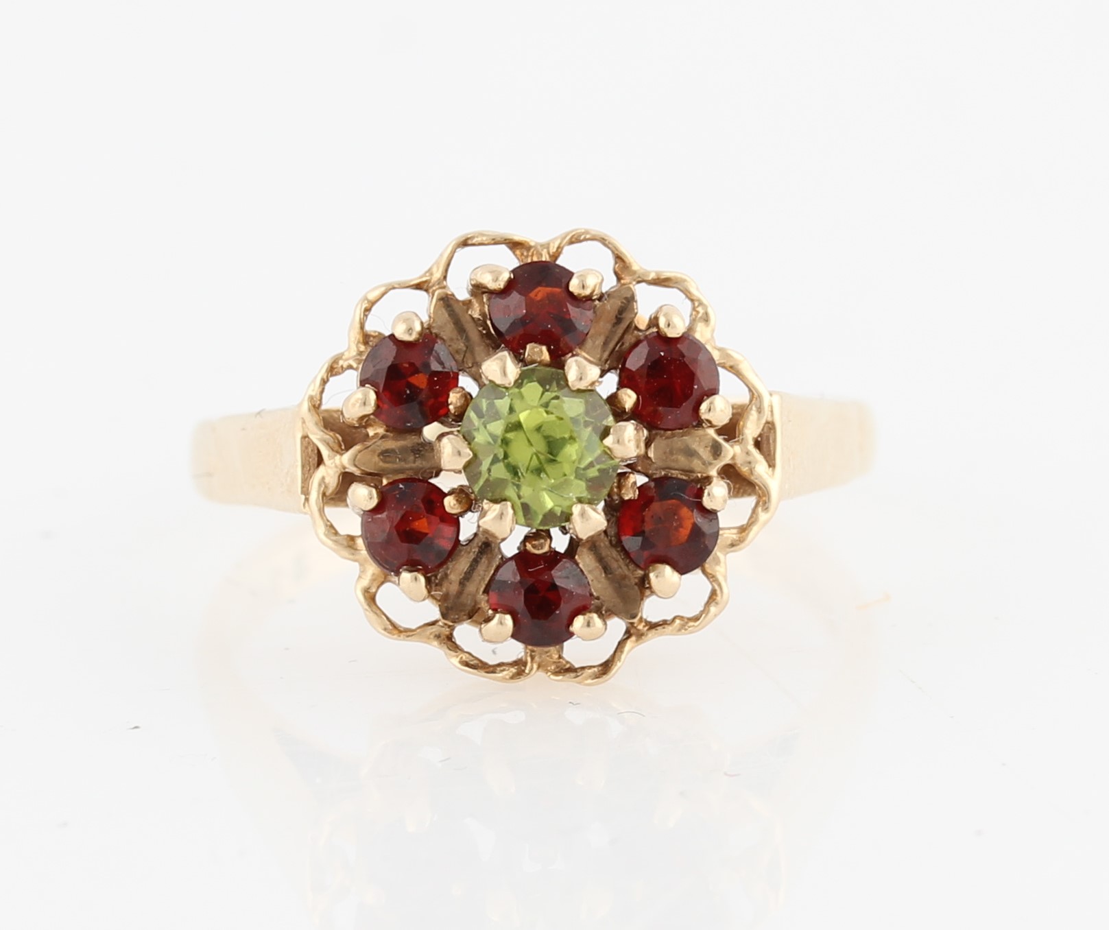 A hallmarked 9ct yellow gold peridot and red stone cluster ring, set with a central round cut