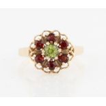 A hallmarked 9ct yellow gold peridot and red stone cluster ring, set with a central round cut