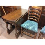 An oak reproduction drop leaf table with three ladderback chairs with blue upholstery.