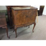 A walnut reproduction two door cocktail cabinet of Queen Anne legs.