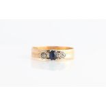 A diamond and sapphire three stone ring, set with a central oval cut sapphire flanked by two old cut