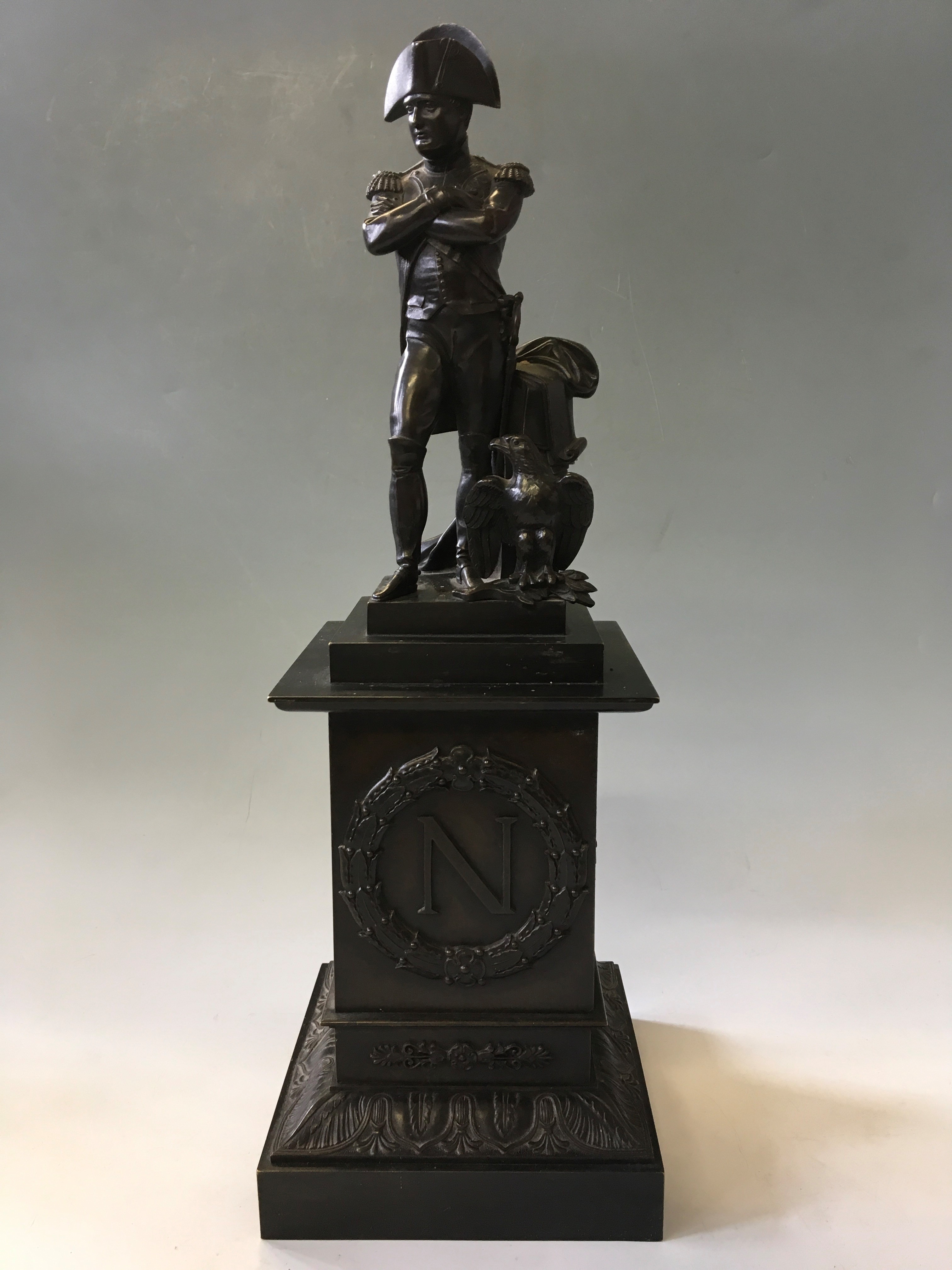 A bronze of Napoleon standing cross armed with an eagle on bronze base with initial stamped to fron